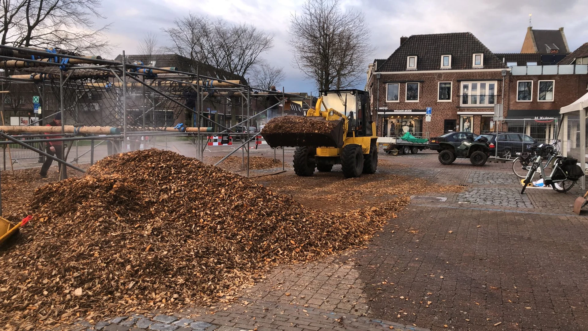 Een shovel verdeelt houtsnippers tussen de hindernissen op het Raadhuisplein.
